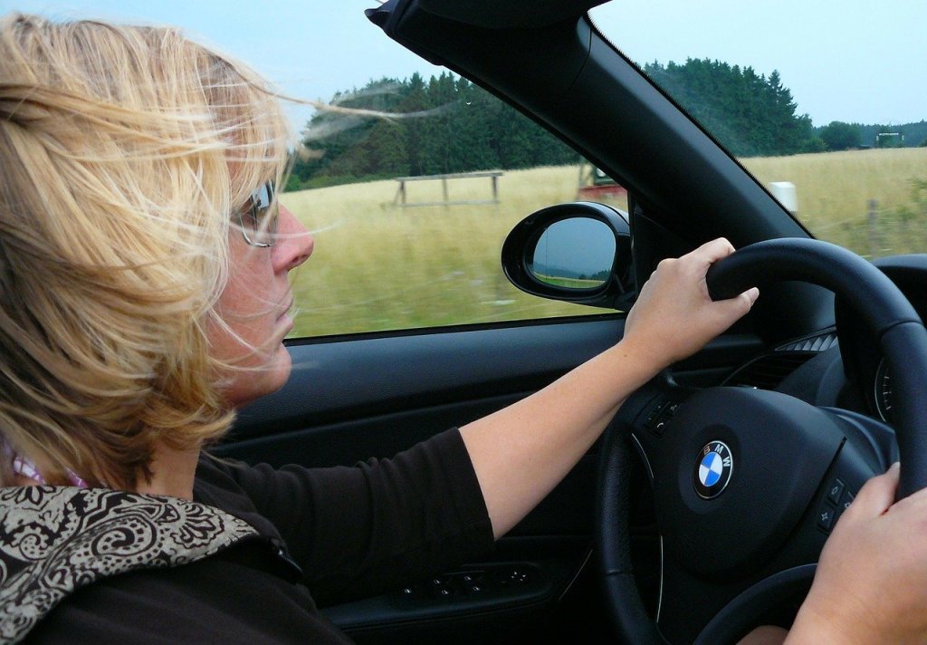 Eine Frau mit Sonnenbrille fährt in einem offenen Cabrio