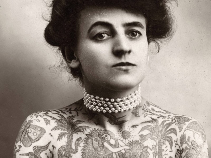 Ein historisches Schwarz-weiß-Foto einer tätowierten Frau, einer sogenannten Tattooed Lady.