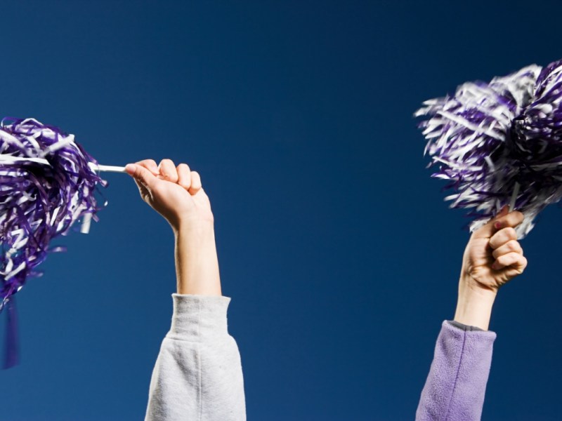 Zwei Hände halten Pom-Poms bei einem Cheerleader-Tanz in die Luft.