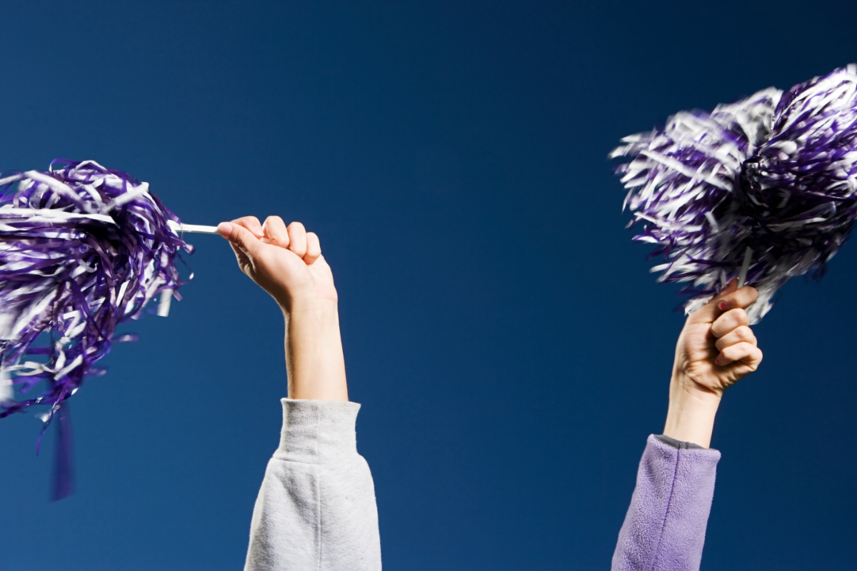 Zwei Hände halten Pom-Poms bei einem Cheerleader-Tanz in die Luft.