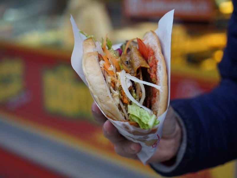 Ein Mann hält einen Döner Kebab in der Hand.